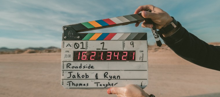 Pair of hands holding film clapperboard in front of desert setting